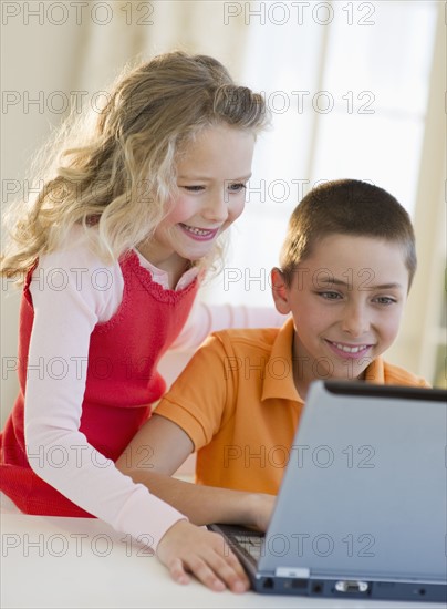 Siblings looking at laptop.