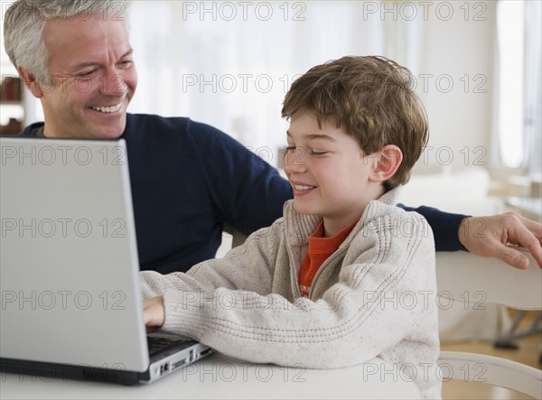 Father and son using laptop. Photographe : Jamie Grill