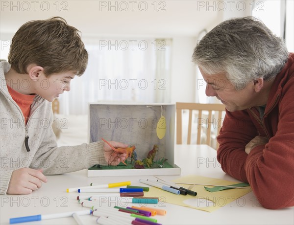 Father and son working on dinosaur project. Photographe : Jamie Grill