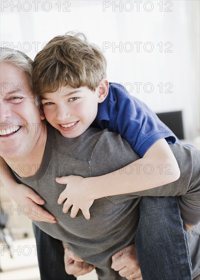 Father giving son piggy back ride. Photographe : Jamie Grill