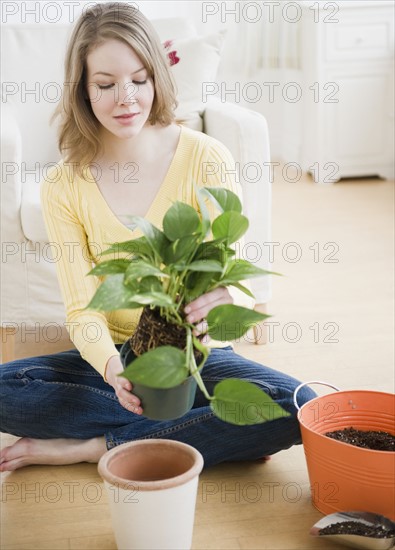 Woman replanting a houseplant. Photographe : Jamie Grill