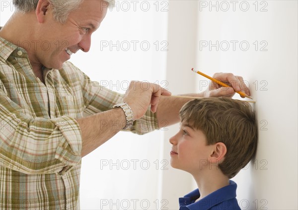 Father measuring son's growth. Photographe : Jamie Grill