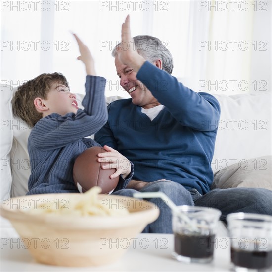 Father and son watching football game. Photographe : Jamie Grill