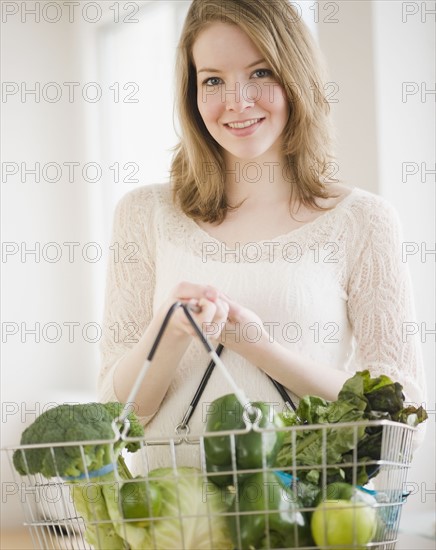 Woman holding basket of green vegetables. Photographe : Jamie Grill