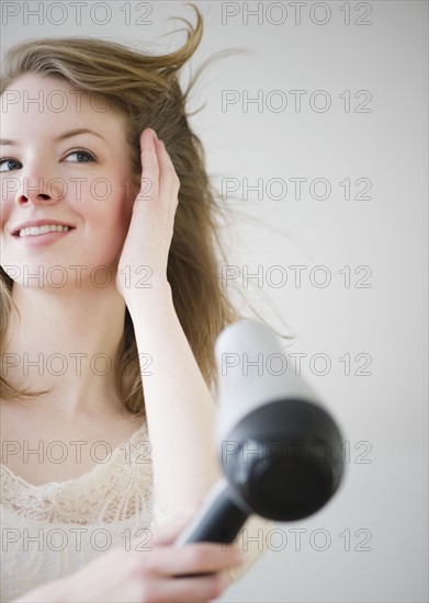 Woman blow drying hair. Photographe : Jamie Grill