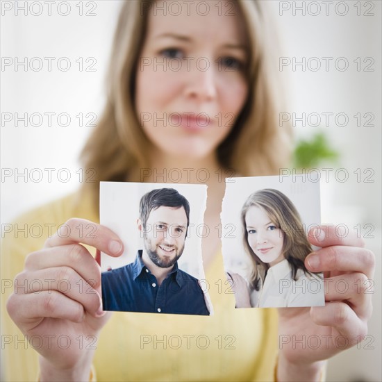 Woman holding torn photograph. Photographe : Jamie Grill