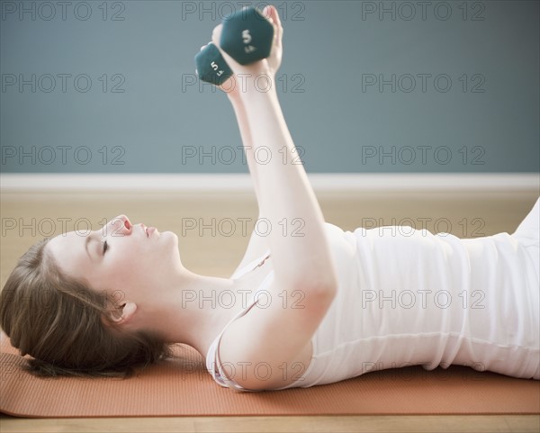 Woman exercising with dumbbells. Photographe : Jamie Grill
