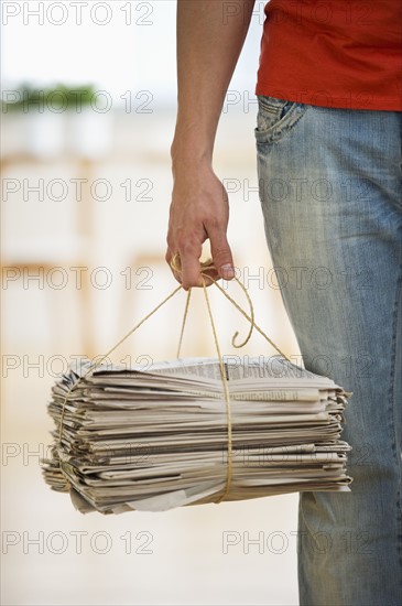 Man holding stack of newspapers. Photographe : Daniel Grill