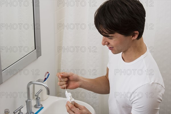 Man flossing his teeth. Photographe : Daniel Grill