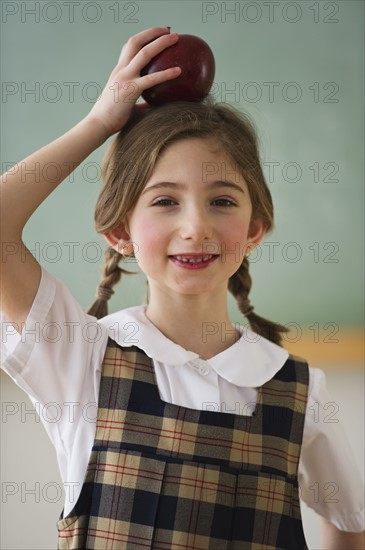 Child holding an apple on her head. Photographe : Daniel Grill