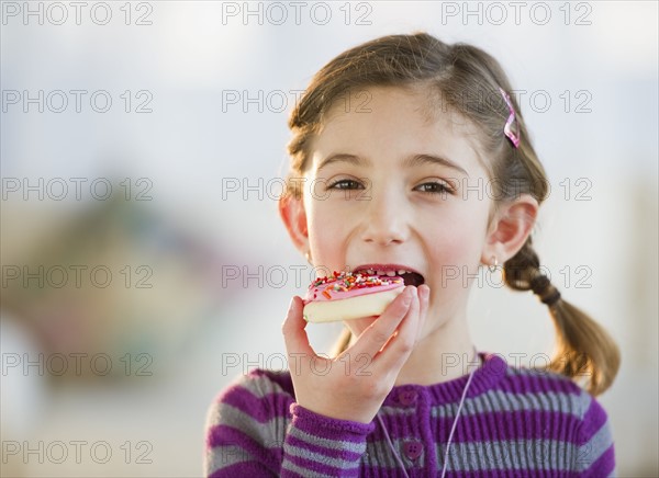 Young girl eating a cookie. Photographe : Daniel Grill