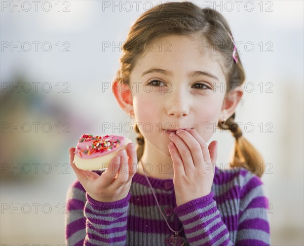 Young girl eating a cookie. Photographe : Daniel Grill