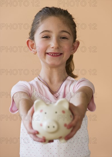 Young girl holding a piggy bank. Photographe : Daniel Grill