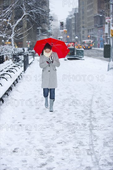 Woman walking with red umbrella on snowy day. Photographe : Daniel Grill