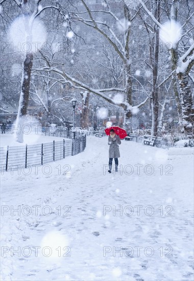 Woman walking with red umbrella on a snowy day. Photographe : Daniel Grill