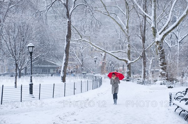 Woman walking with red umbrella on a snowy day. Photographe : Daniel Grill