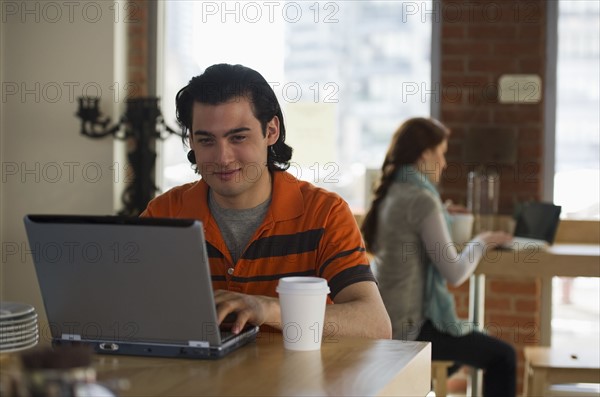 Man working on laptop in coffee shop. Photographe : Daniel Grill