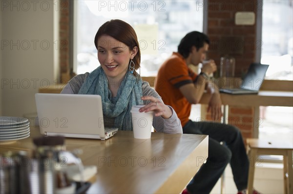 Woman working on laptop in coffee shop. Photographe : Daniel Grill