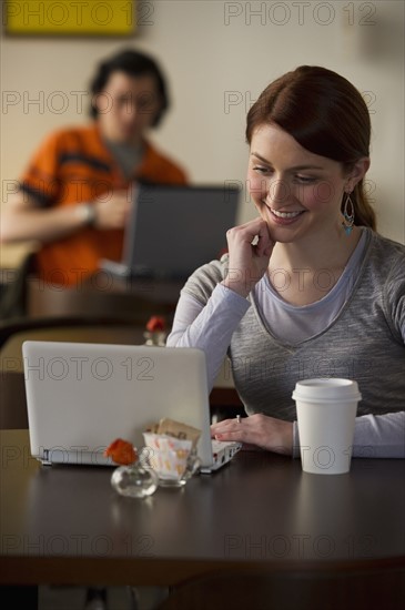 Woman working on laptop in coffee shop. Photographe : Daniel Grill