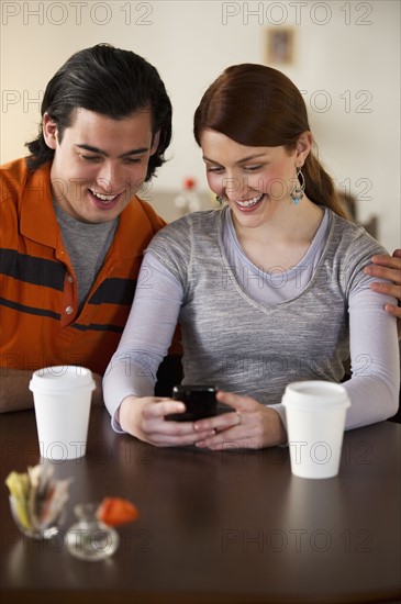 Couple reading text on cellular phone. Photographe : Daniel Grill