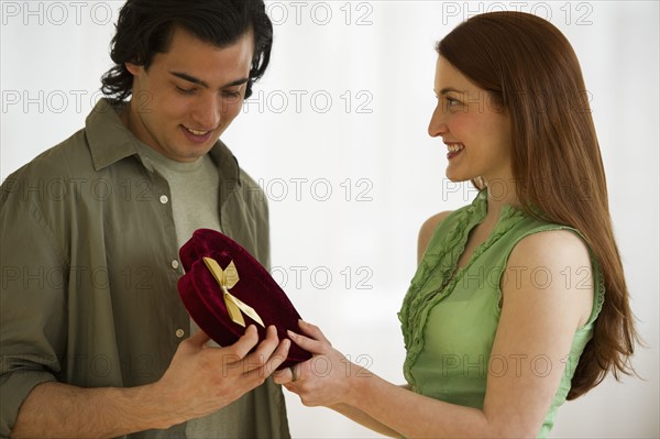 Woman giving box of chocolates to man. Photographe : Daniel Grill