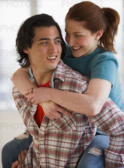 Man giving woman a piggy back ride. Photographe : Daniel Grill