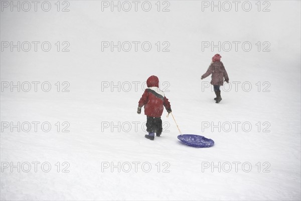 Kids pulling sled up snowy hill. Photographe : fotog