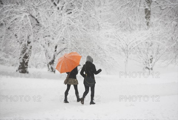 Two girls walking through snowy park. Photographe : fotog