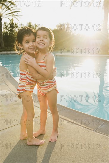 Sisters standing beside pool.