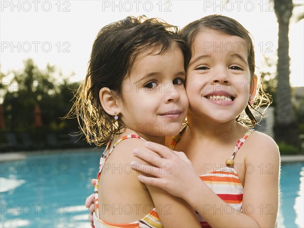 Sister embracing beside pool.