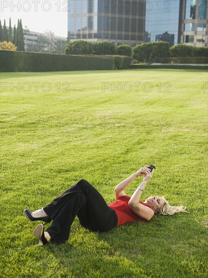 Woman lying on grass and texting.