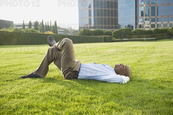Businessman relaxing on lawn.