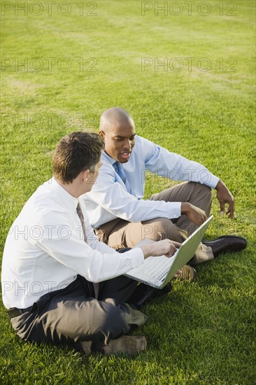 Co-workers sitting on grass.