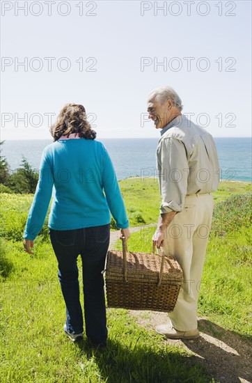 Couple carrying picnic basket to the beach.