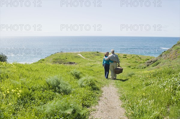 Couple carrying picnic basket to the beach.