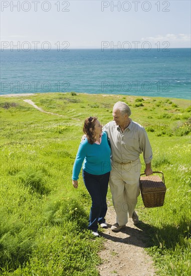 Couple carrying picnic basket to the beach.