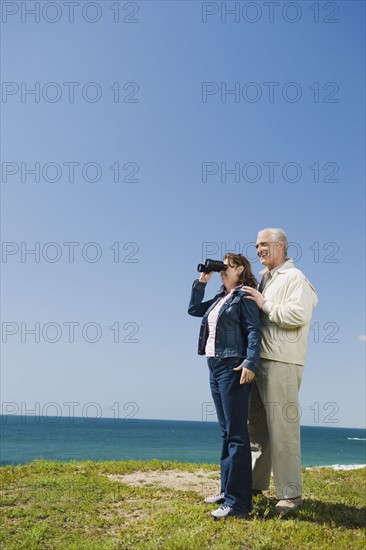 Couple looking at ocean with binoculars.