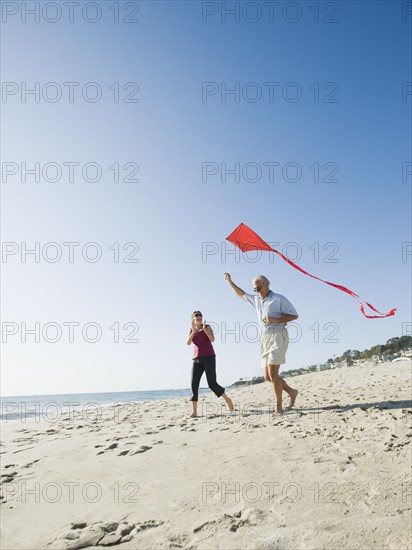 Couple flying kite on beach.