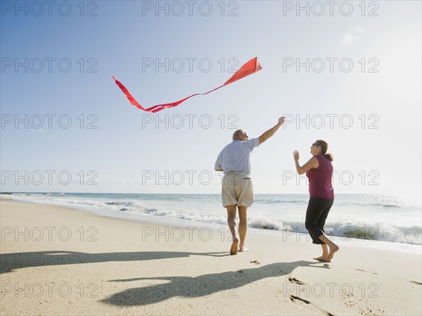 Couple flying kite on beach.