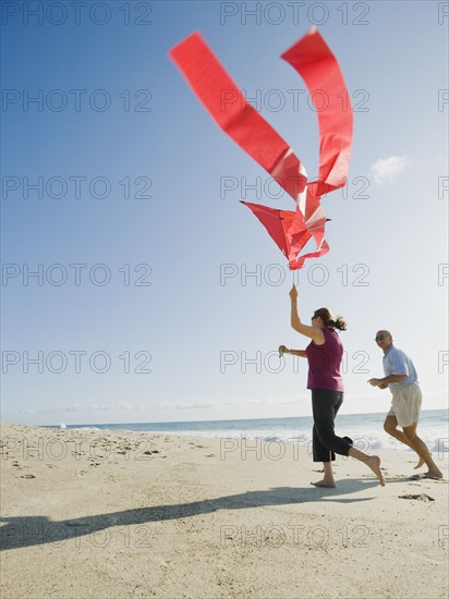 Couple flying kite on beach.