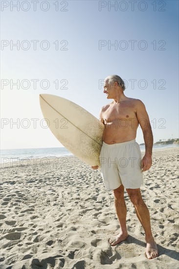 Man holding surfboard on beach.