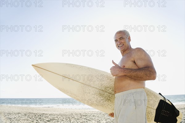 Man holding surfboard on beach.