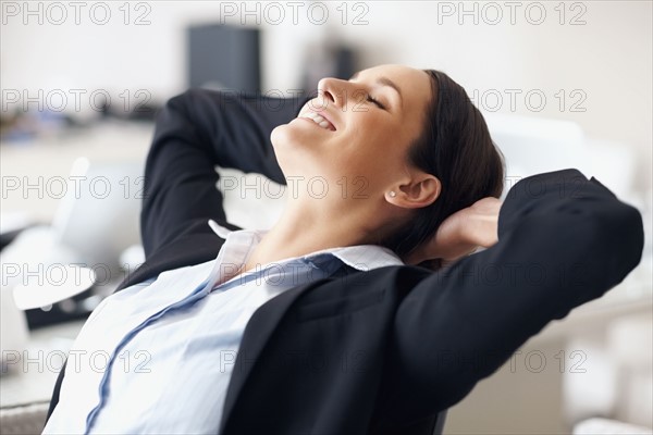 Businesswoman stretching at desk. Photographe : momentimages