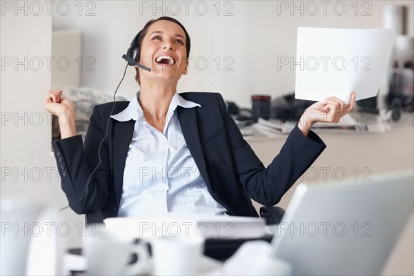 Businesswoman laughing while wearing headset. Photographe : momentimages