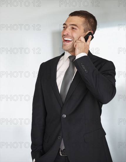 Businessman talking on cellular phone. Photographe : momentimages