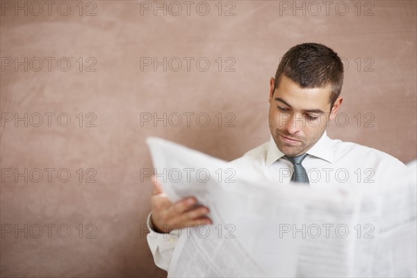 Businessman reading newspaper. Photographe : momentimages