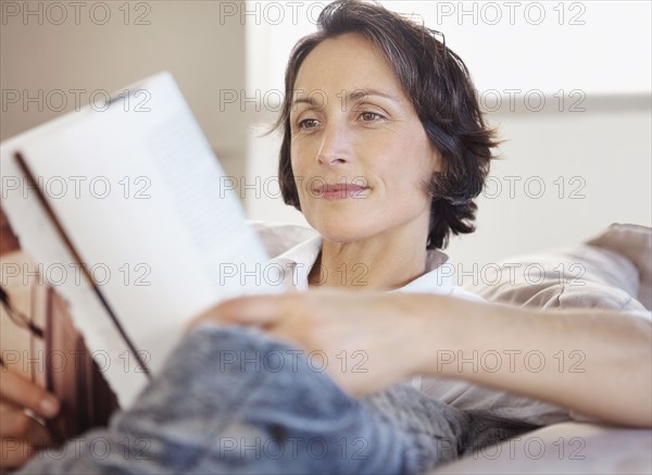 Woman reading on couch. Photographe : momentimages