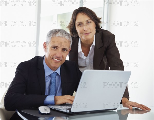 Colleagues looking at laptop. Photographe : momentimages