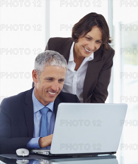 Colleagues looking at laptop. Photographe : momentimages