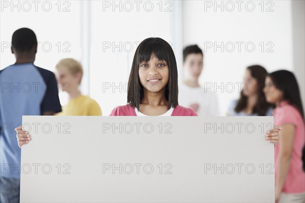 Young student holding blank billboard. Photographe : momentimages